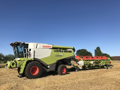 Photo of a Mahindra combine harvester in a golden wheat field under a clear blue sky.