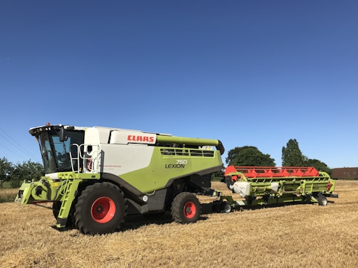 A row of combine harvesters parked neatly, shining under the clear sky.
