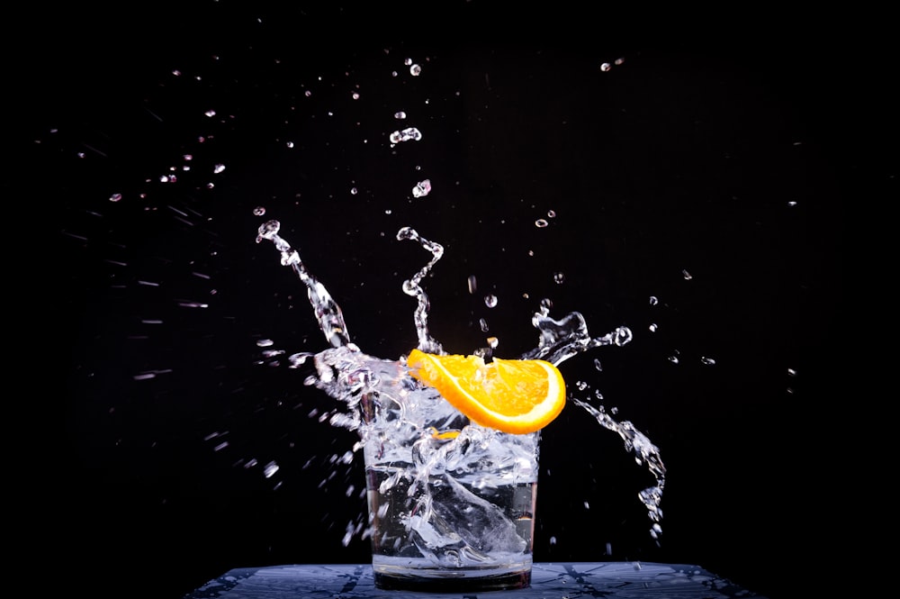 splash of water in drinking glass with sliced lemon
