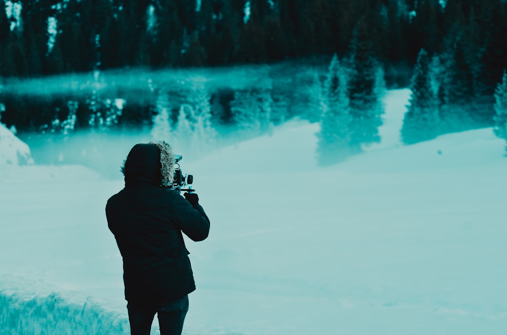Mann trägt schwarze Kapuzenjacke, während er auf schneebedecktem Weg steht