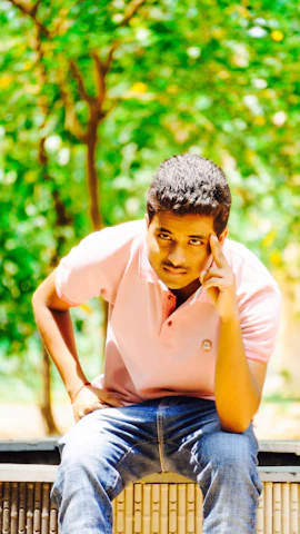A candid shot of a young person wearing a muted green Roze Pulse t-shirt, standing on a sunlit Bengaluru street with modern buildings and greenery in the background.