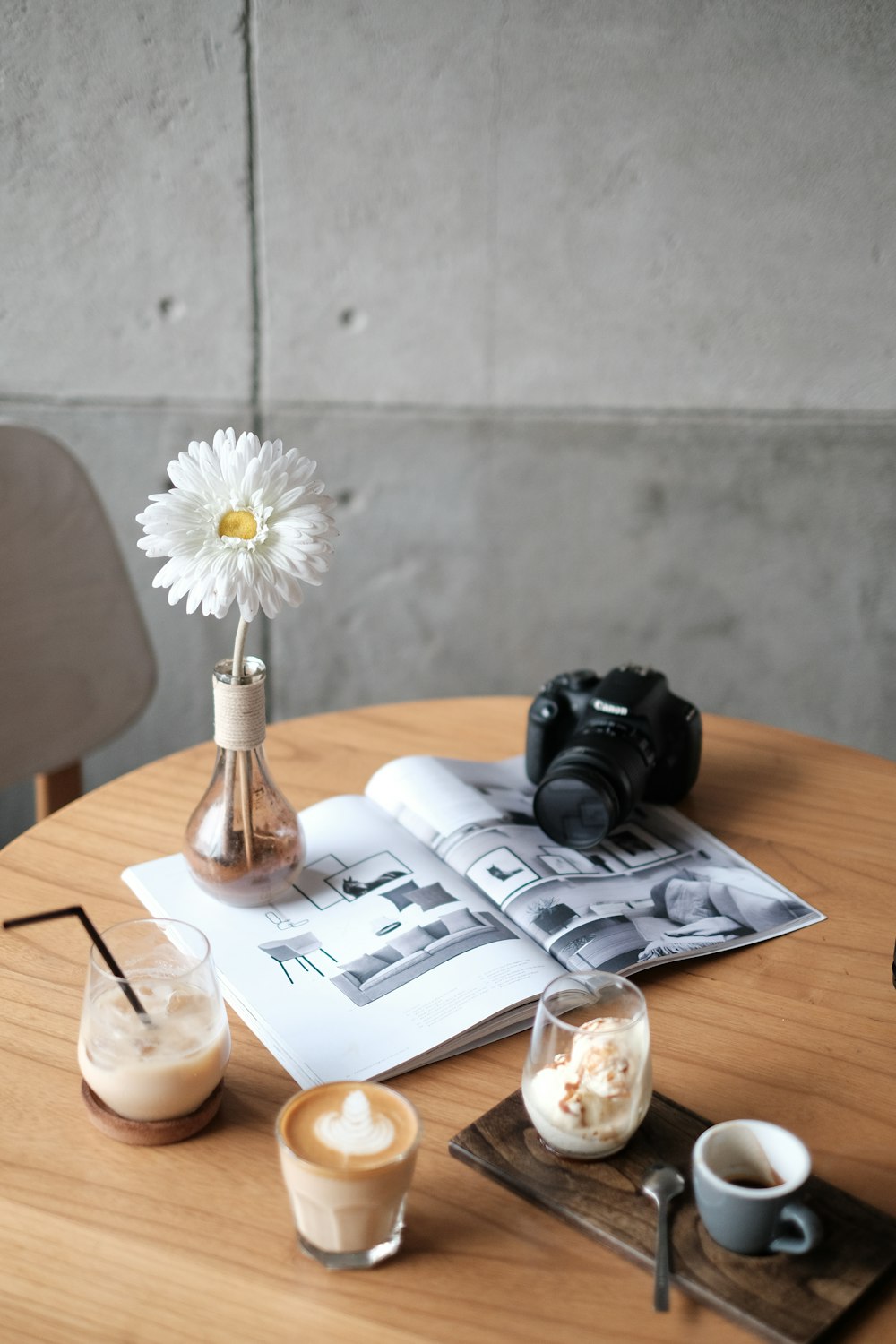 cámara Canon DSLR negra en un libro blanco junto a una flor blanca