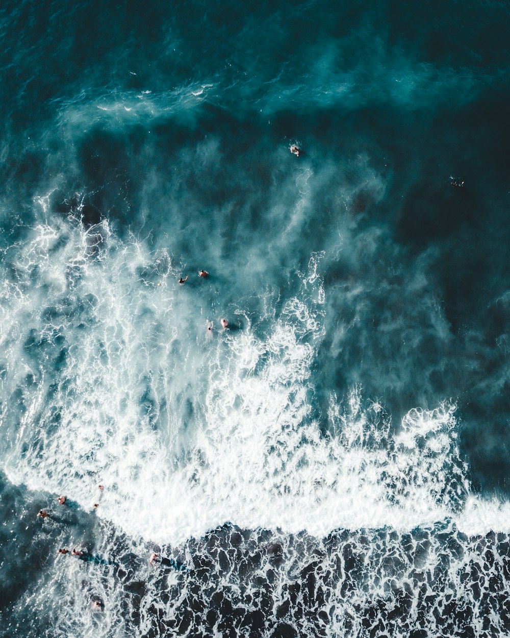 people bathing on body of water with waves during daytime