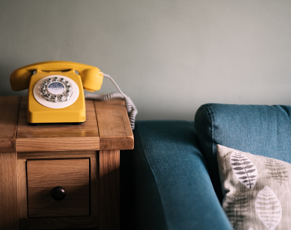 Photo d’un téléphone à cadran jaune près d’un canapé bleu