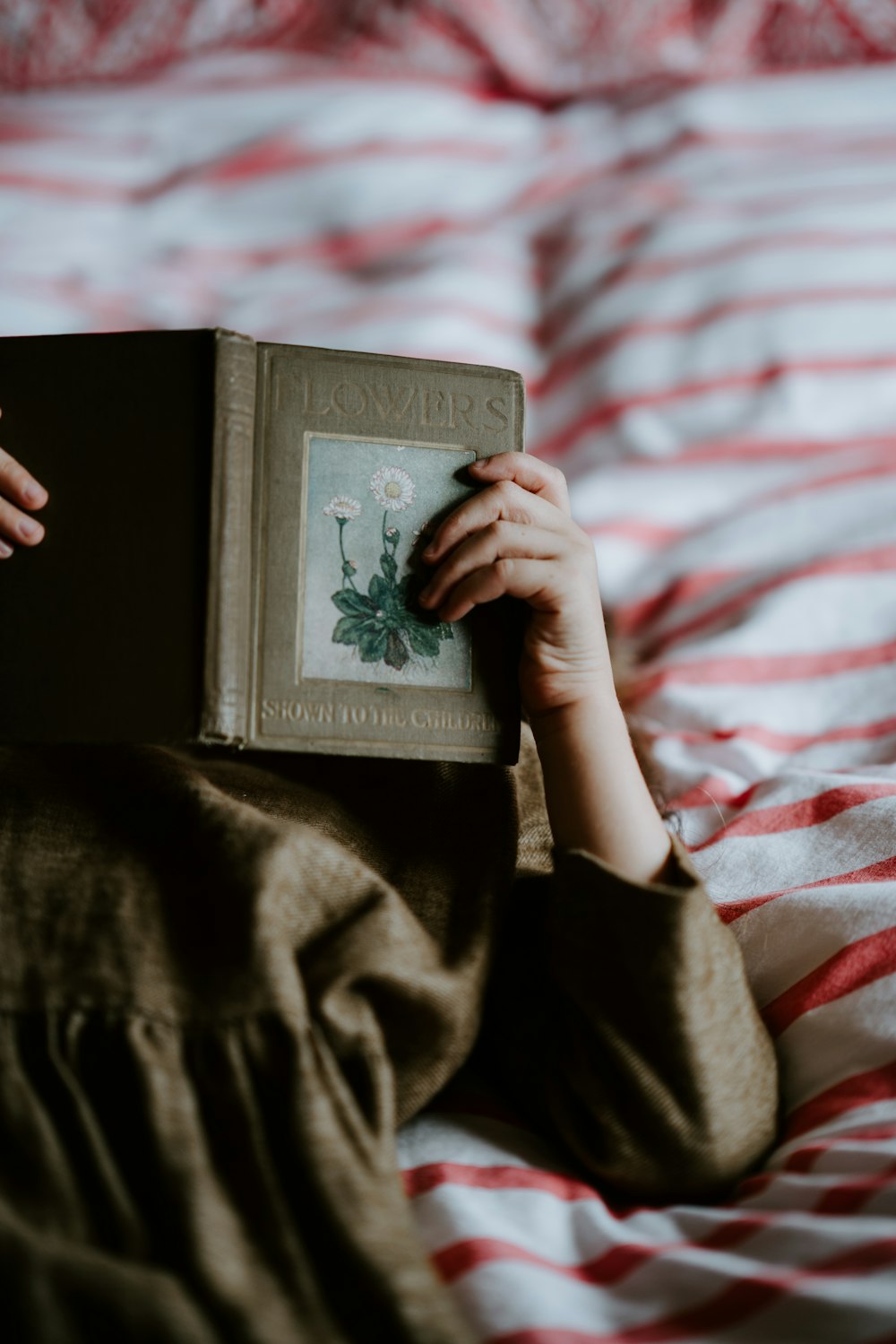 person laying on bed while reading a book