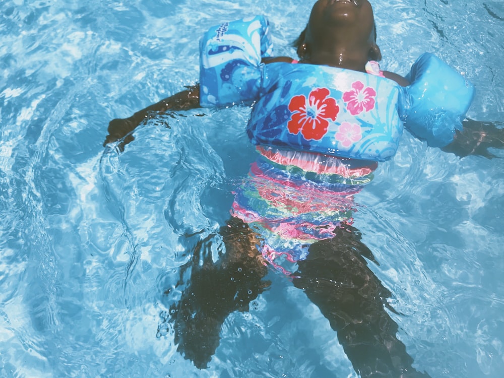 toddler wearing blue floral pool float on swimming pool
