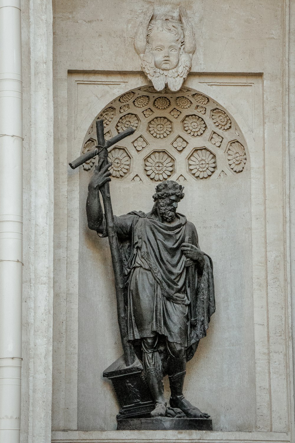 black concrete statue on man holding cross