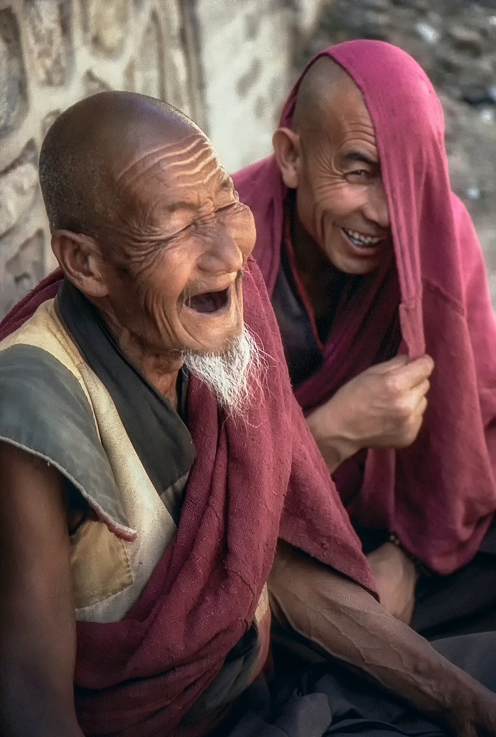 two laughing men near gray wall during daytime