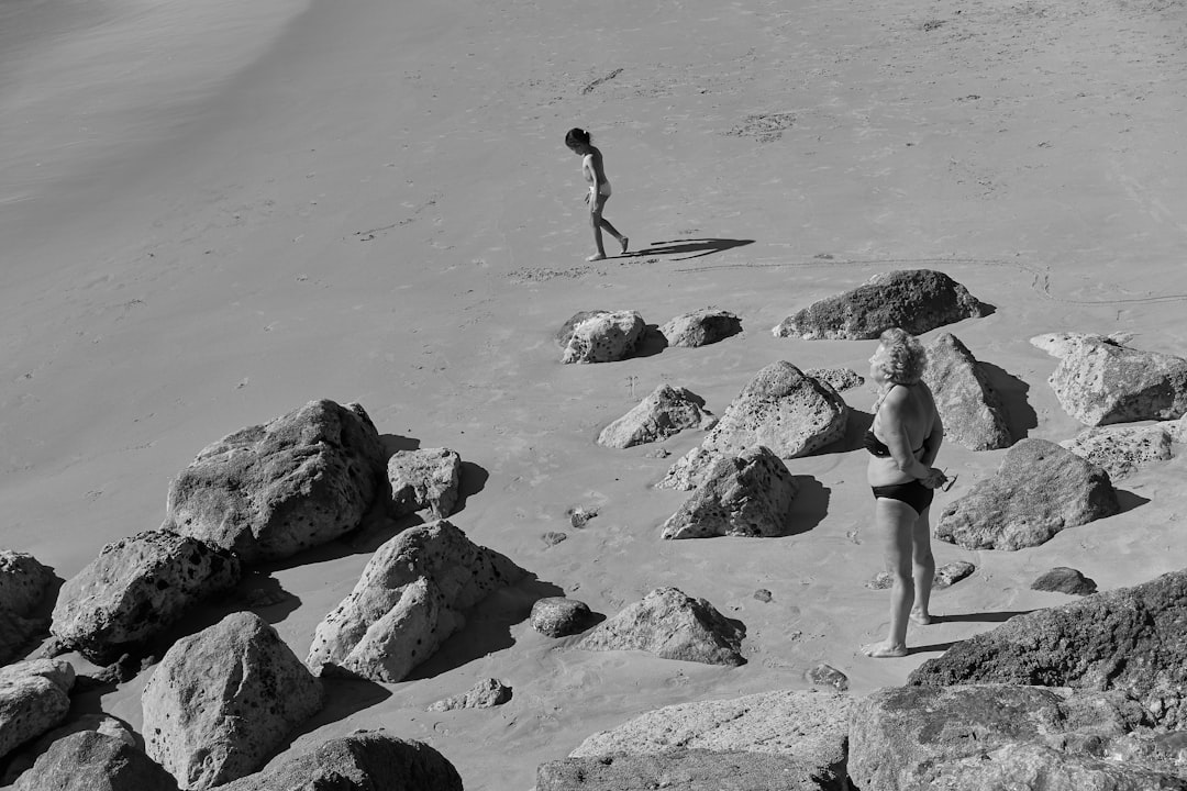 grayscale photo of two person near body of water,