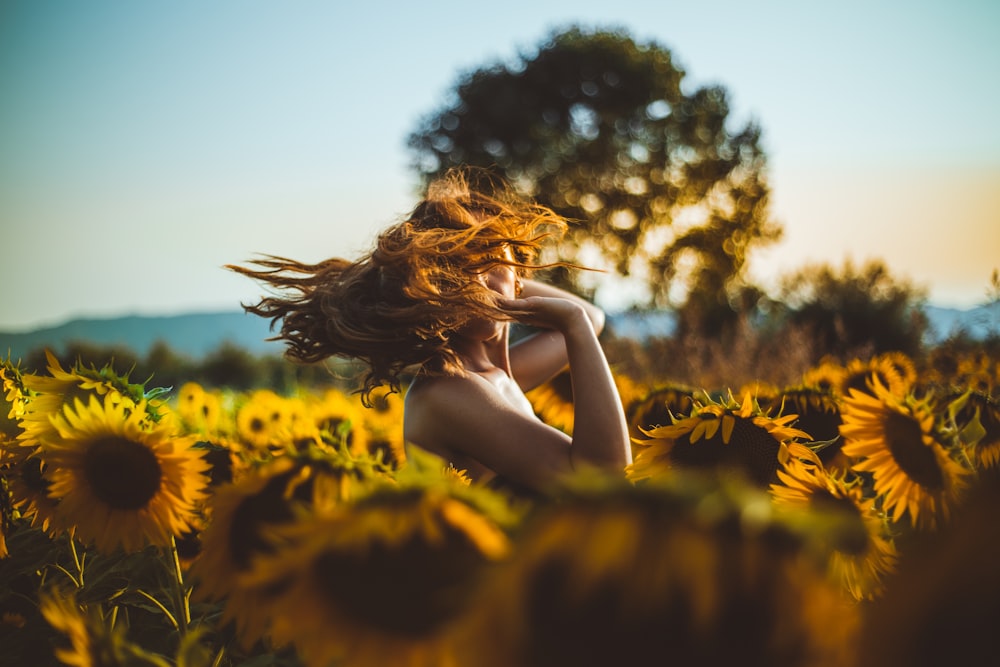 Frau steht mitten im Sonnenblumenfeld