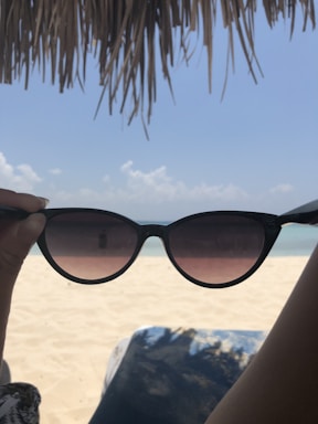 Stylish sunglasses displayed against a bright sunny beach backdrop, highlighting their sleek design.