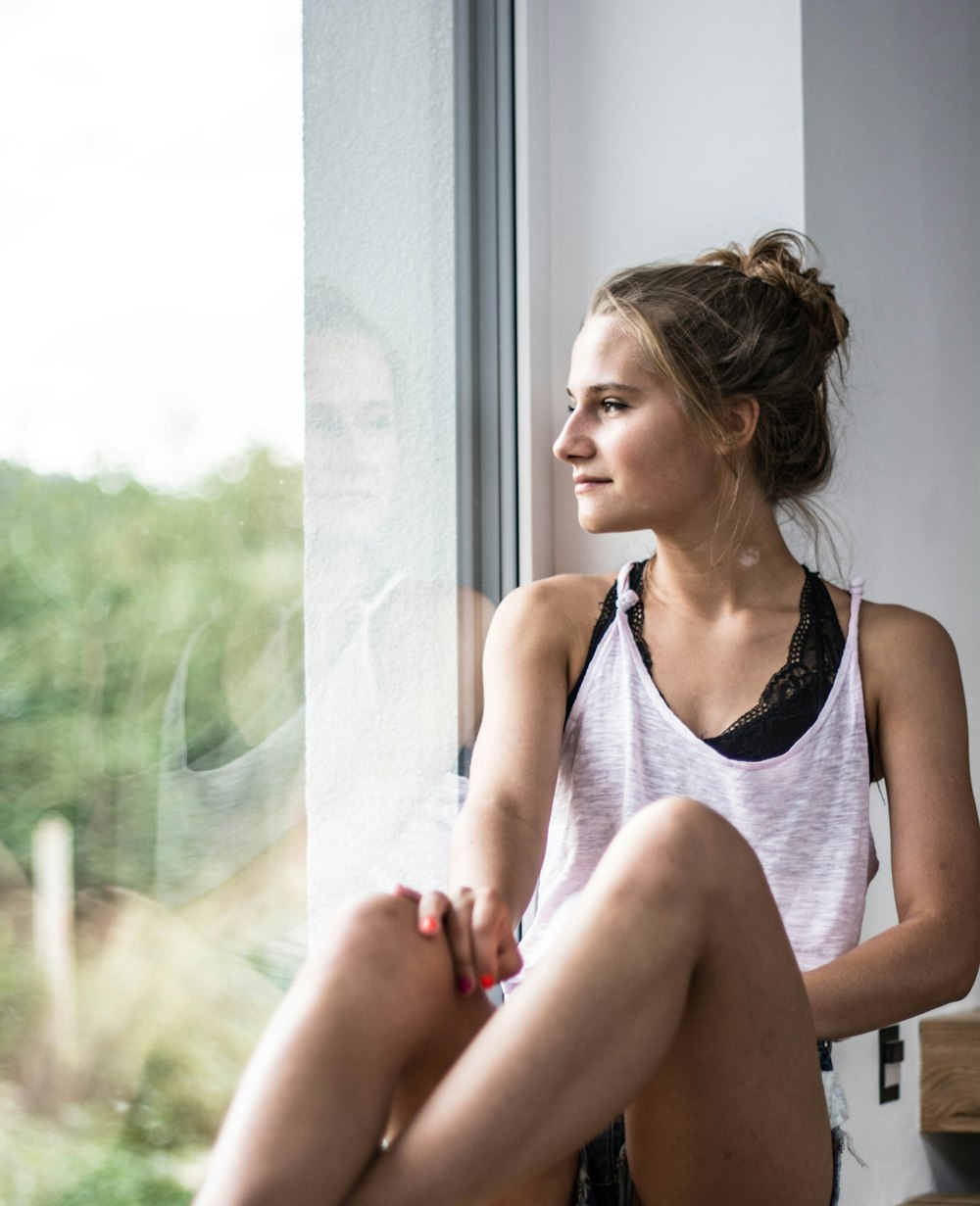 woman sitting beside window overlooking trees