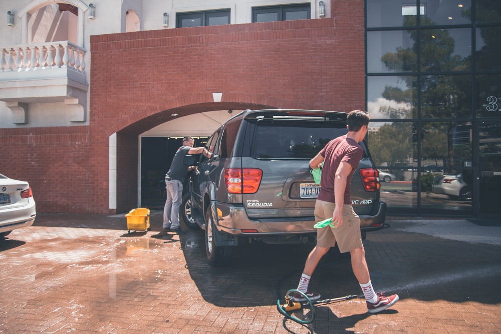 man cleaning silver SUV