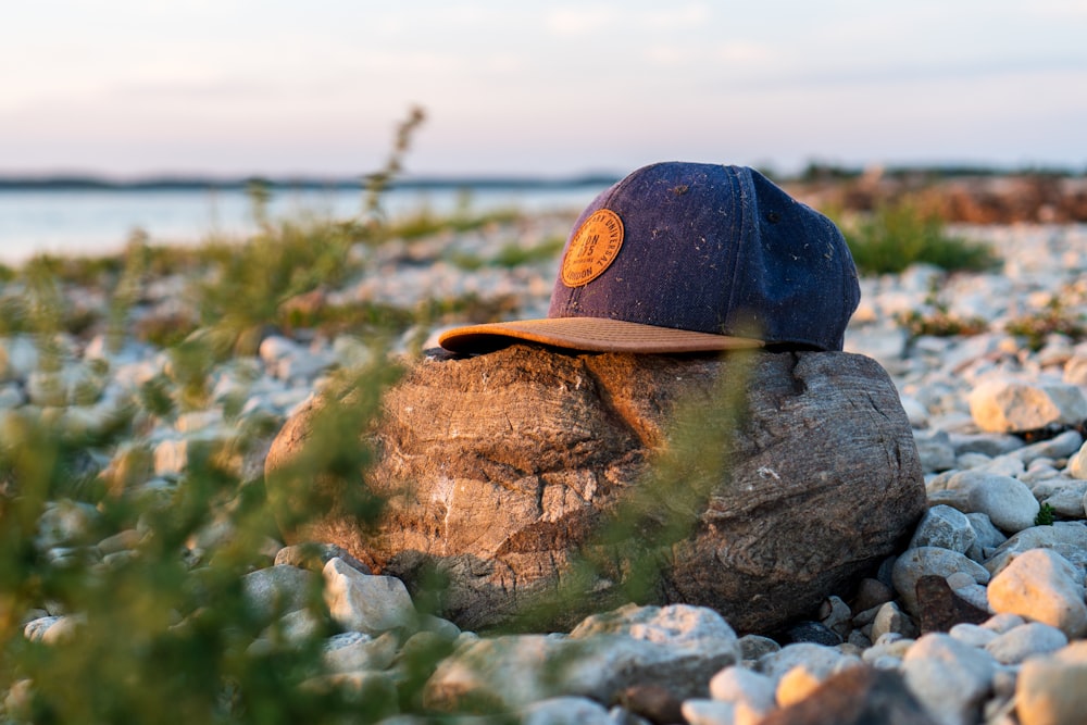 Sombrero de ala plana azul y marrón sobre roca marrón