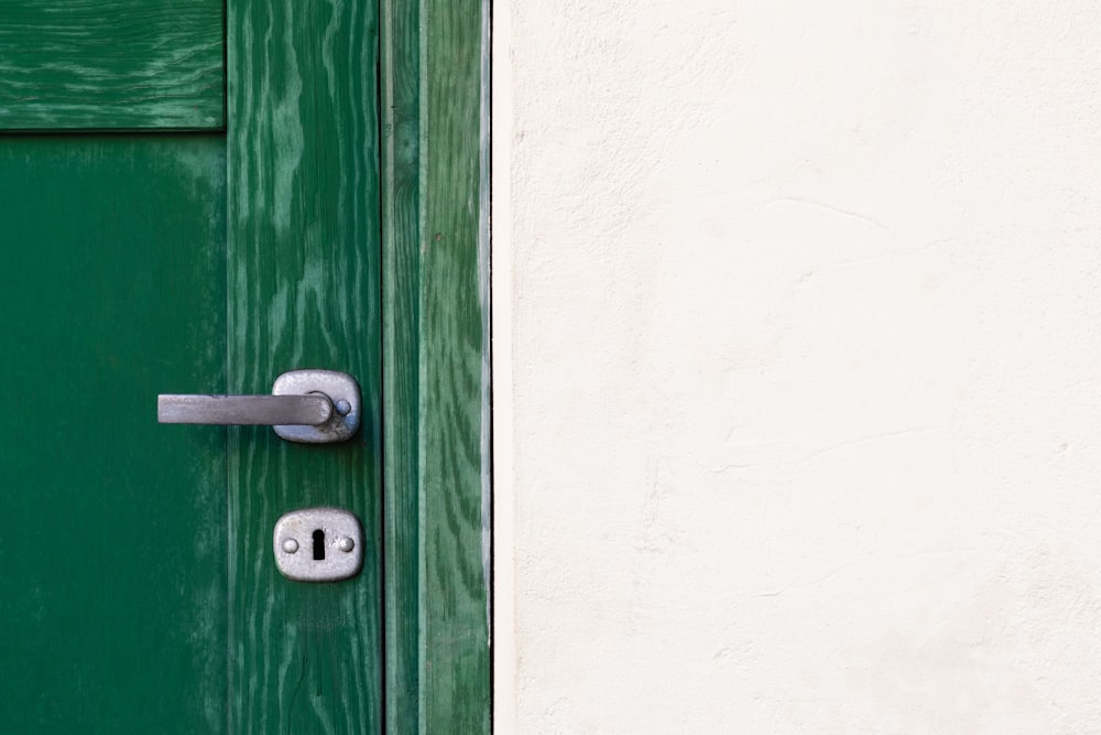 green wooden door beside white wall