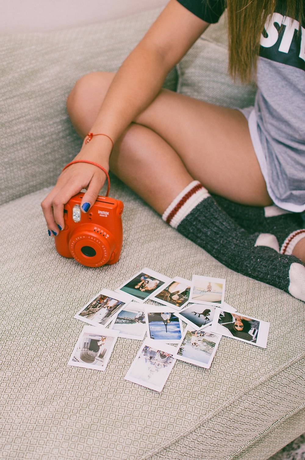 person sitting on couch holding red instant camera