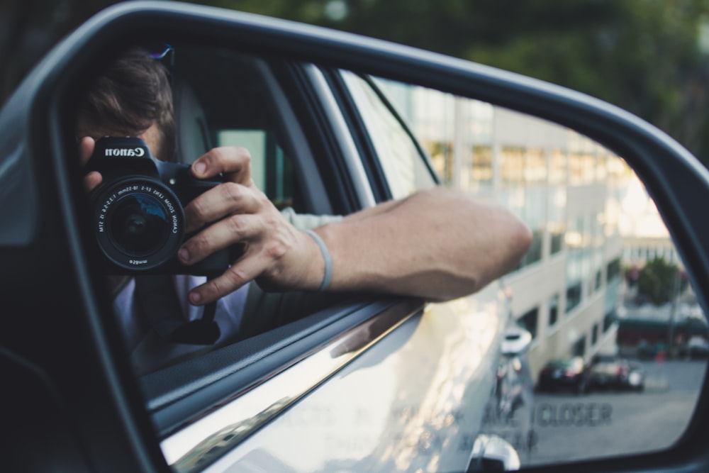 person holding black Canon DSLR camera