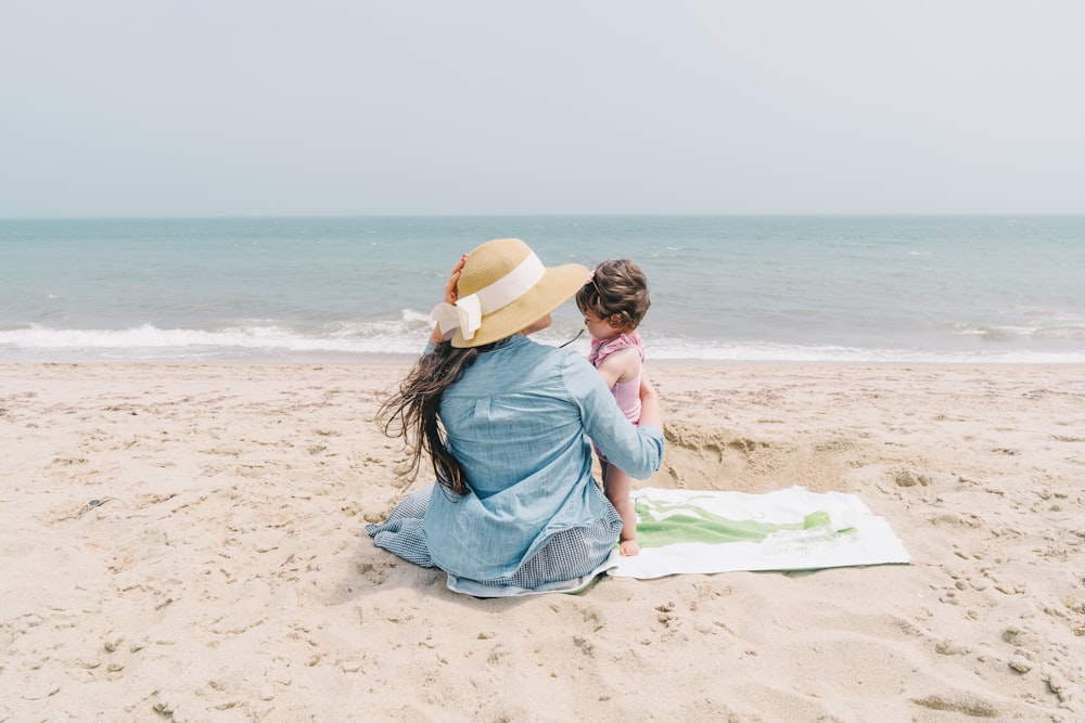 Mujer sosteniendo niño pequeño en la orilla del mar frente