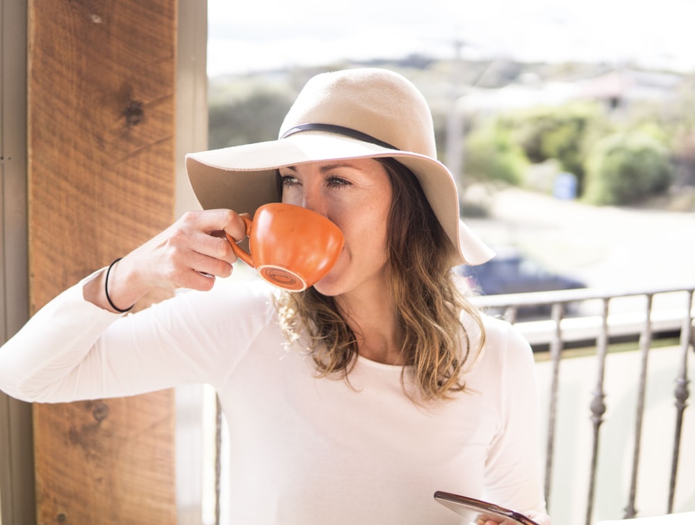 woman sipping from her orange cup