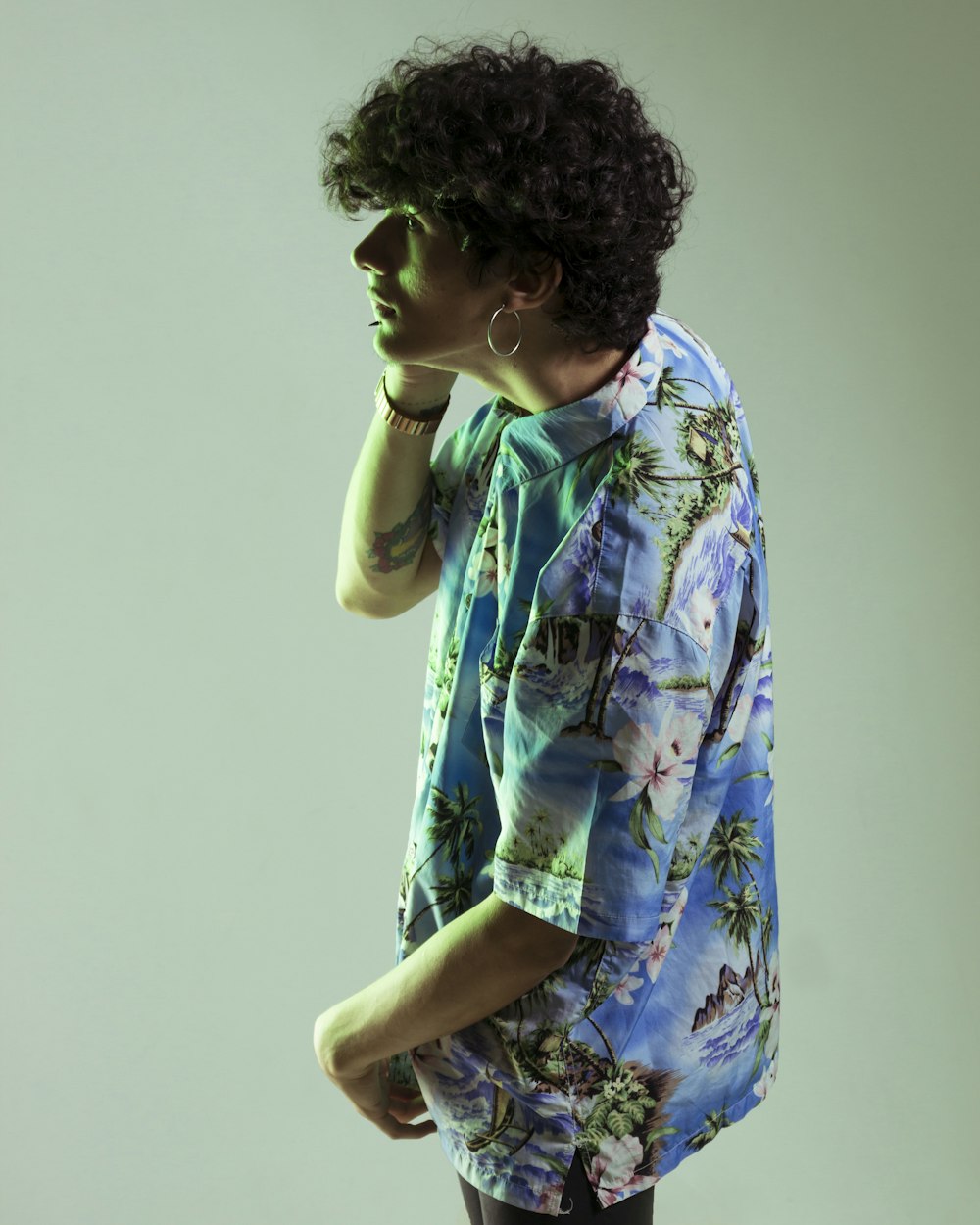 man wearing blue and green floral collared top with white backgrounds