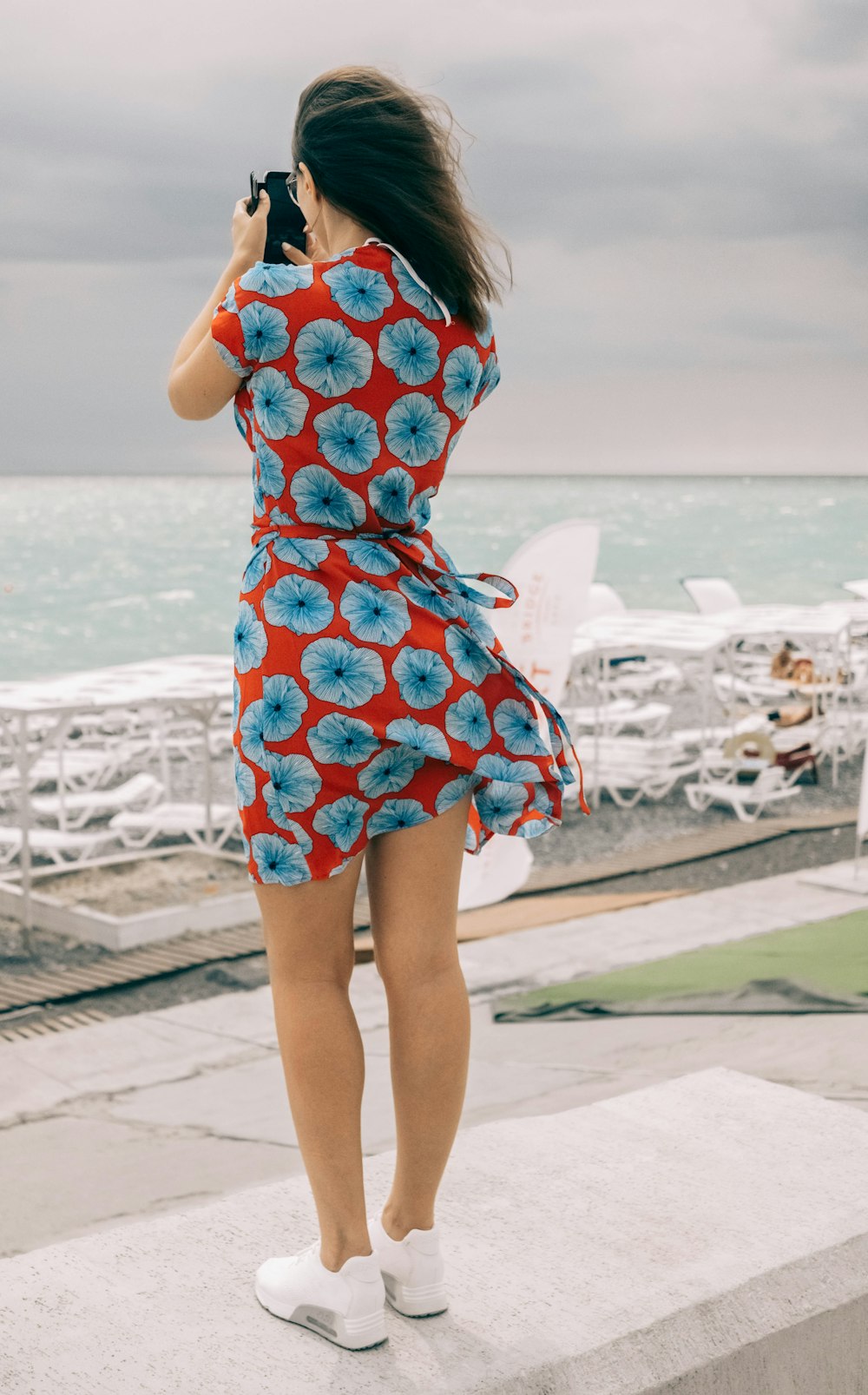 woman wearing maroon and blue floral dress holding phone at daytime