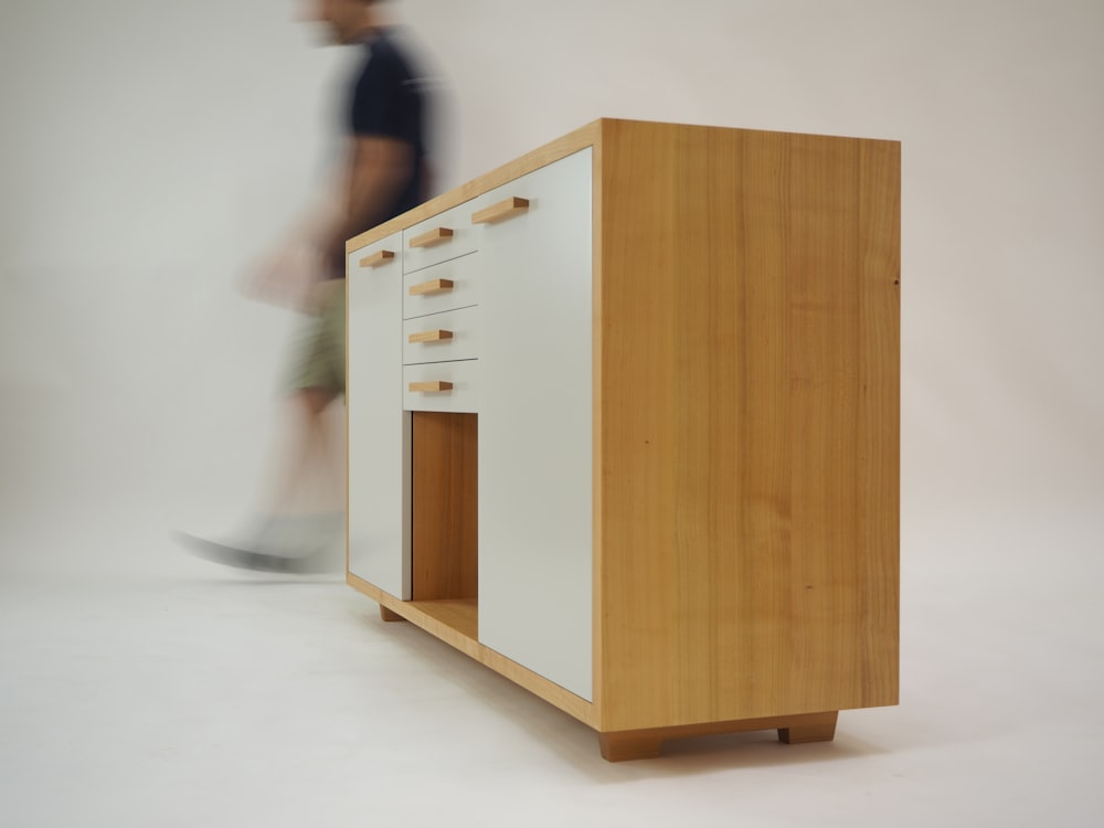 person walking beside white and brown wooden sideboard
