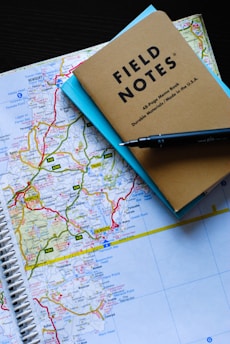 An elegant map spread on a wooden table with notes and bird sketches beside binoculars.
