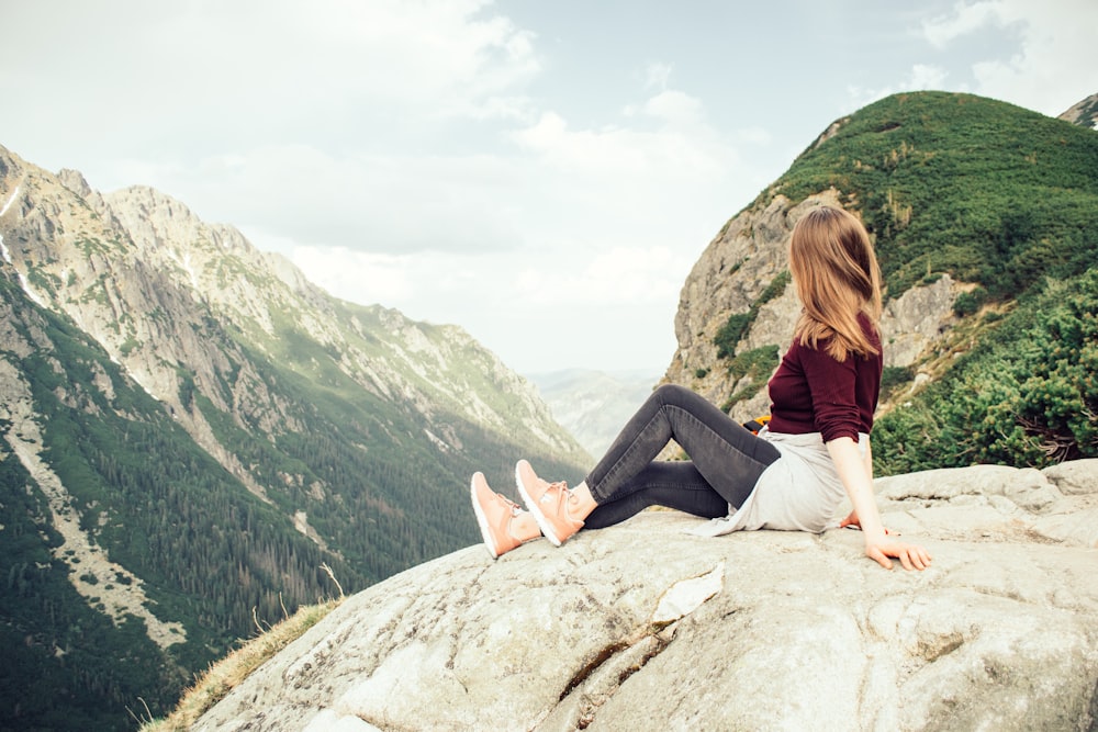 mulher sentada no pico das montanhas