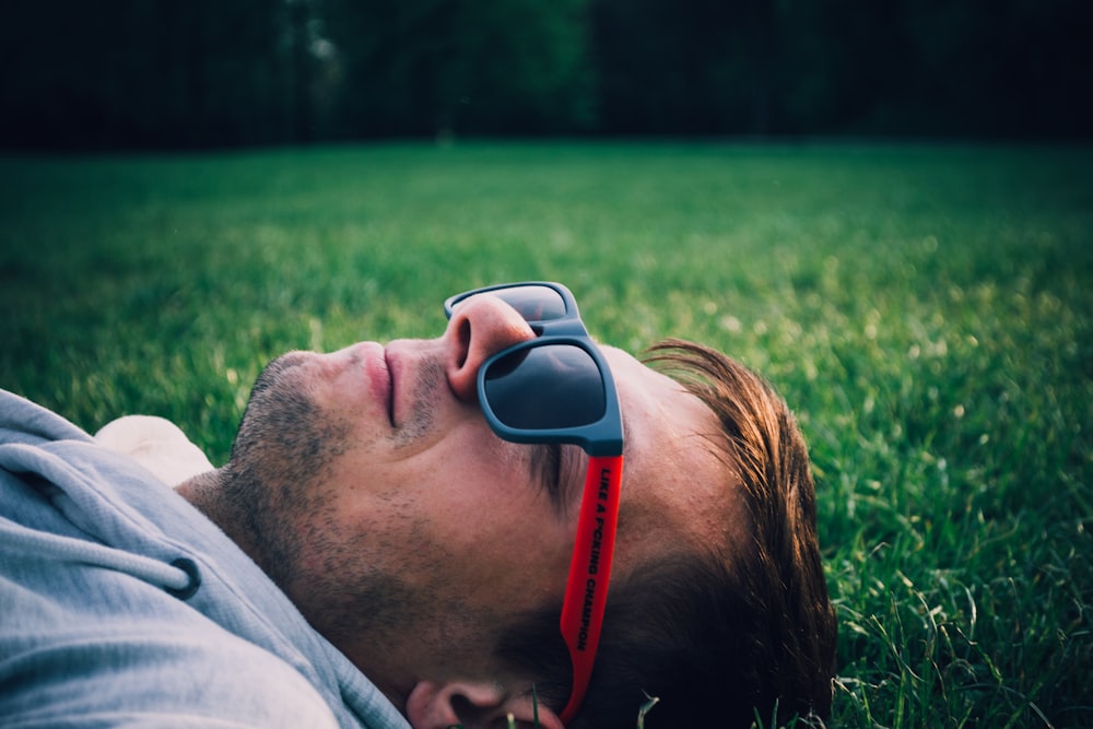 man laying on green grass field