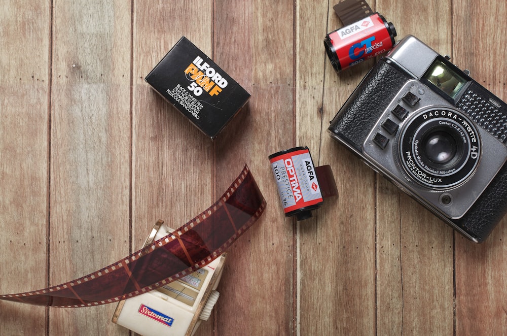 Fotografía plana de cámara de película y películas sobre parquet de madera