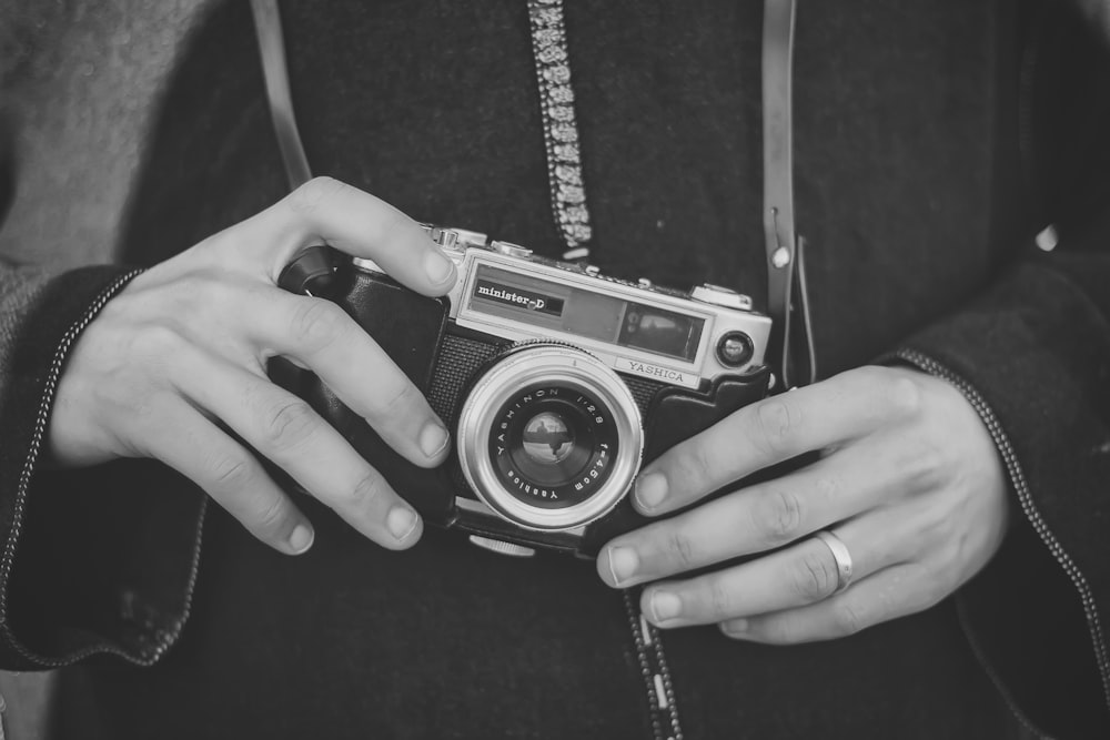 grayscale photo of person holding SLR camera