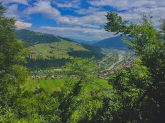 A charming valley surrounded by rolling hills and a distant river.