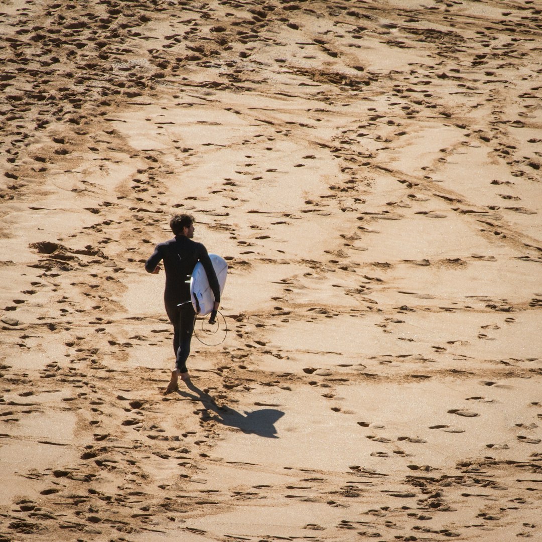 man carrying white surfboard standing on ground