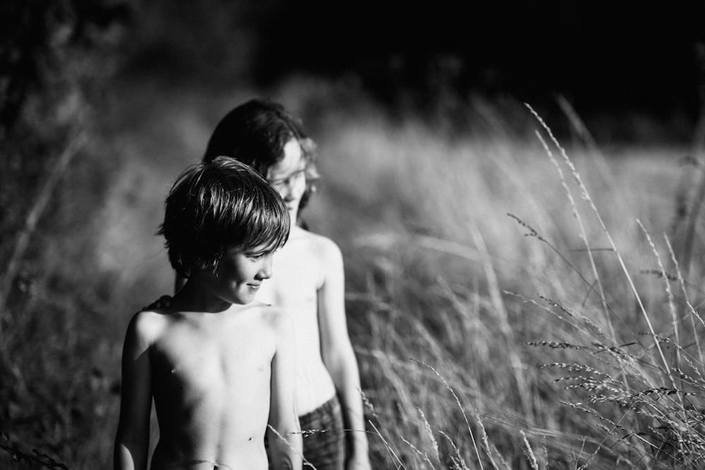 two topless toddlers standing on open field