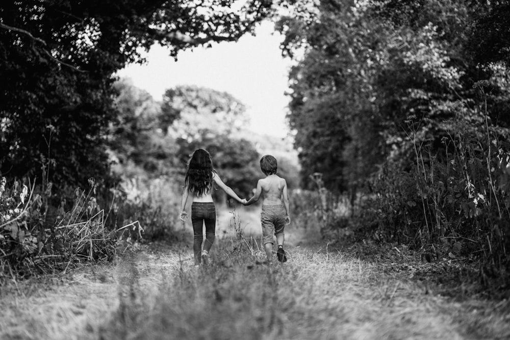 grayscale photo of boy and girl walking on path