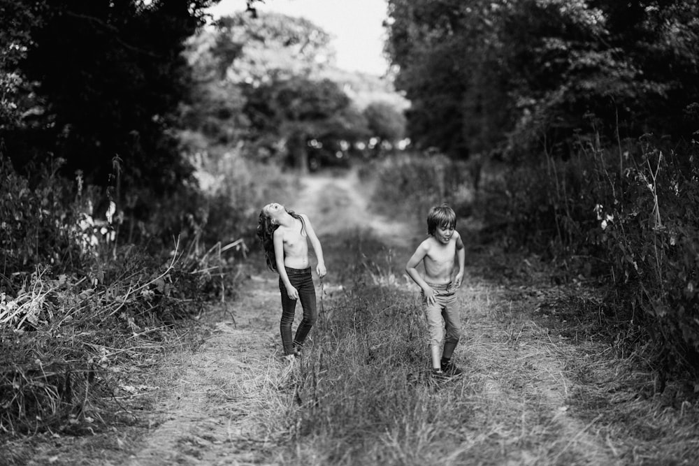 boy and girl on footpath between grass grayscale photography