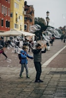 A candid street photo capturing a child playing with bubbles on a sunny day.