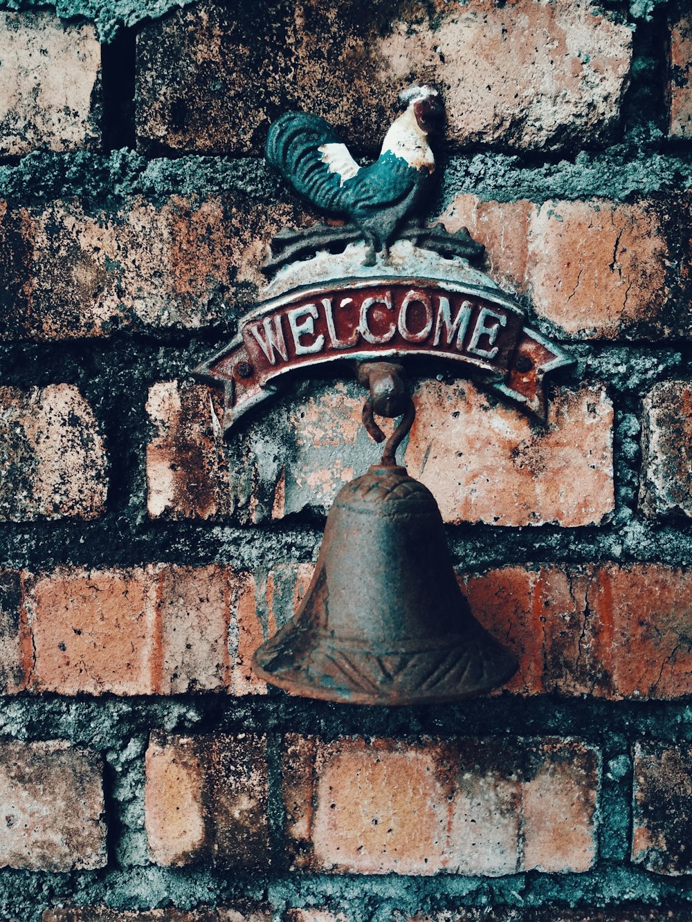brown metal welcome bell on brown brick wall