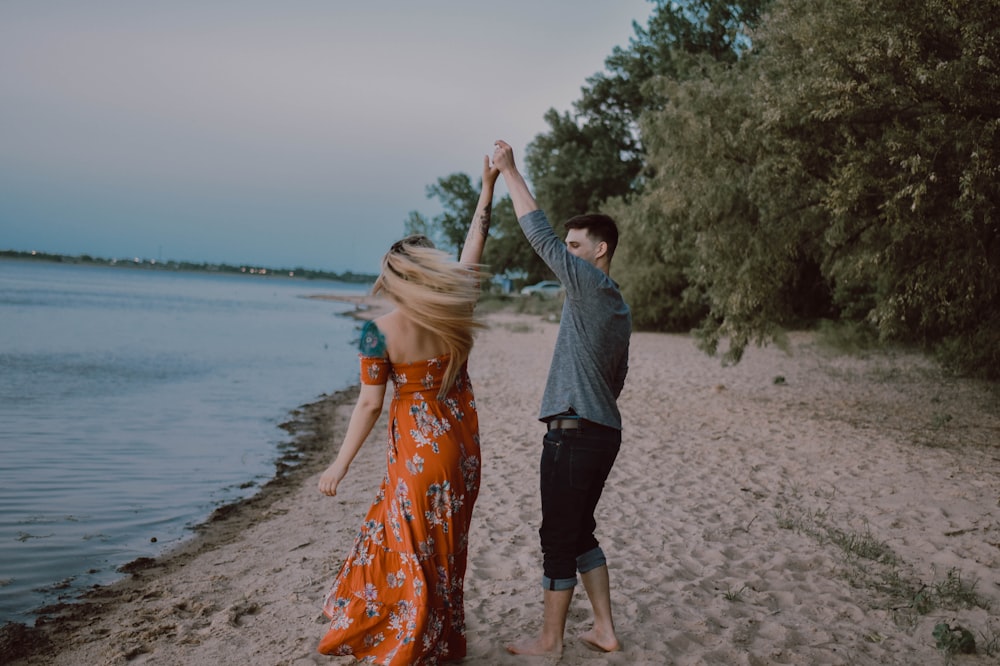 man and woman holding hands near seashore at daytime
