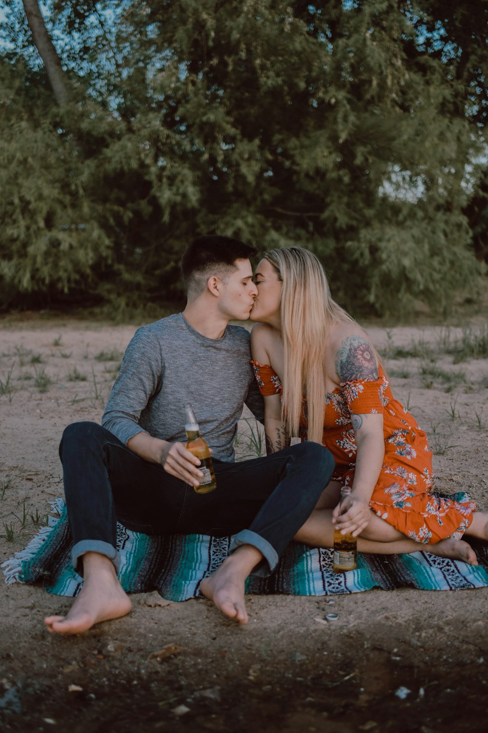 man and woman sitting while kissing on ground