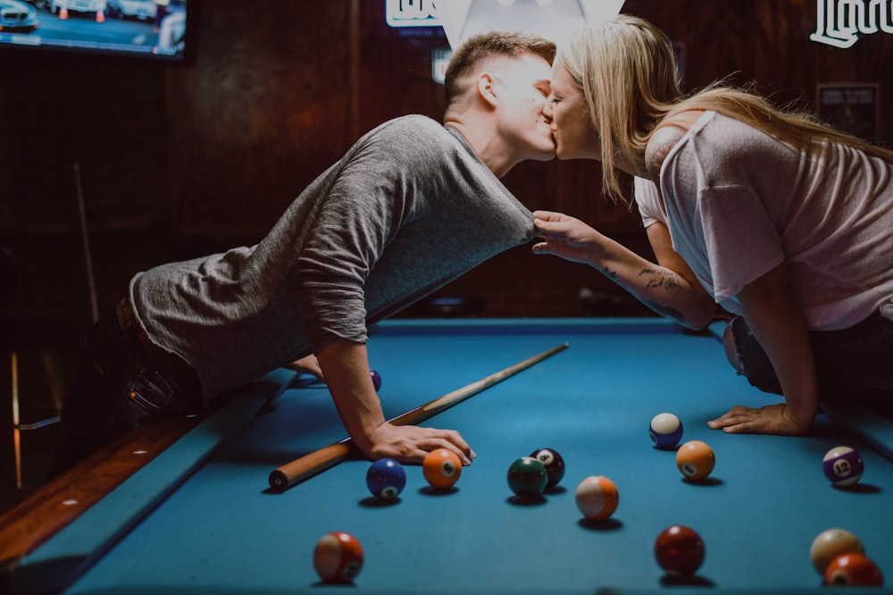 homem e mulher se beijando na mesa de bilhar