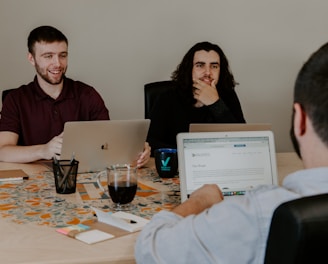 three person sitting in-front of table with laptop computers