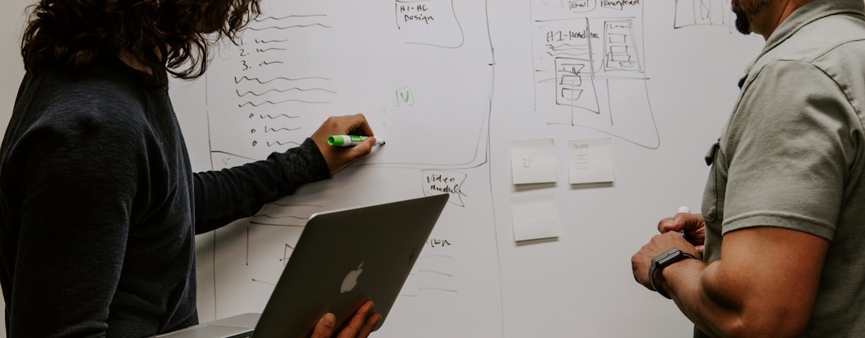 man wearing gray polo shirt beside dry-erase board