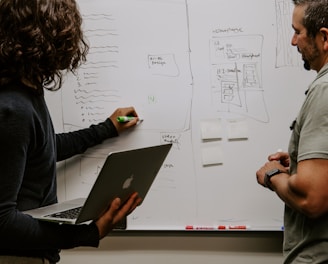 man wearing gray polo shirt beside dry-erase board