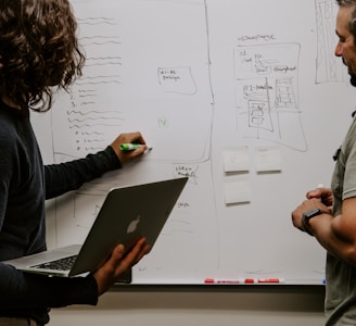 man wearing gray polo shirt beside dry-erase board