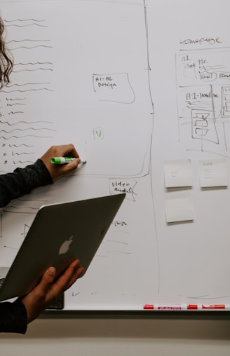 man wearing gray polo shirt beside dry-erase board