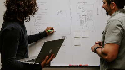 man wearing gray polo shirt beside dry-erase board