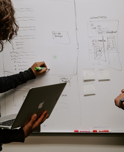 man wearing gray polo shirt beside dry-erase board