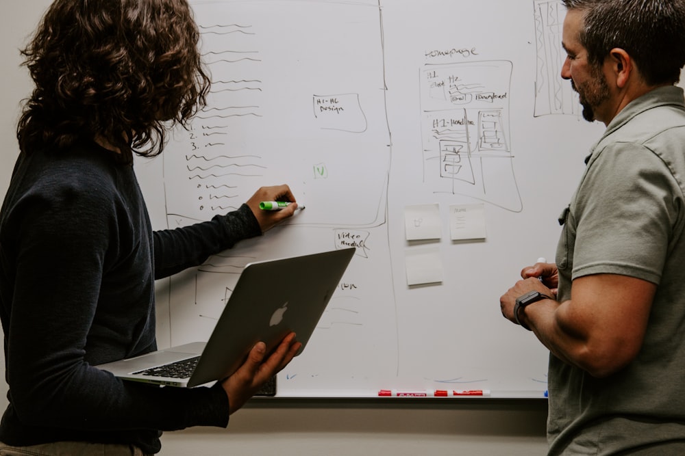 man wearing gray polo shirt beside dry-erase board