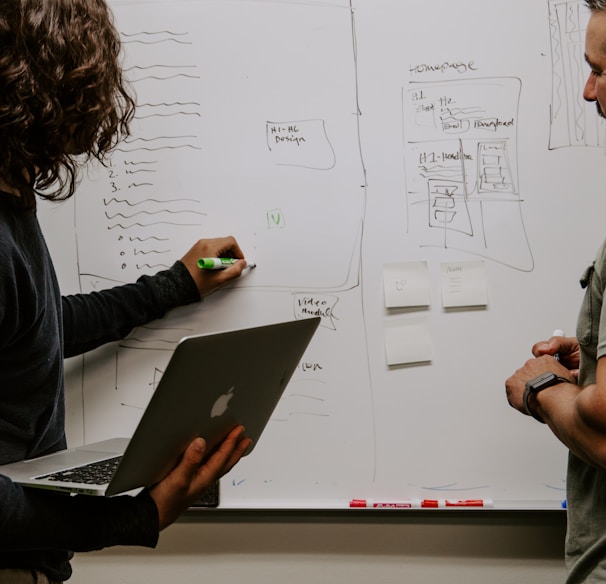 man wearing gray polo shirt beside dry-erase board